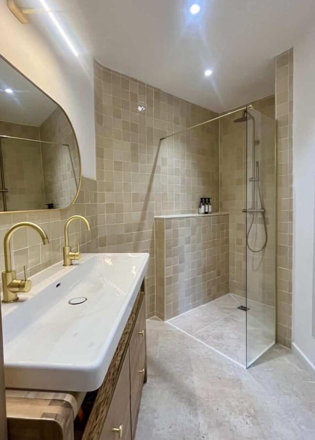 Salle de bain avec douche à l'italienne, double vasque et robinetterie dorée vue de dessus, rénovation Atelier Luzons
