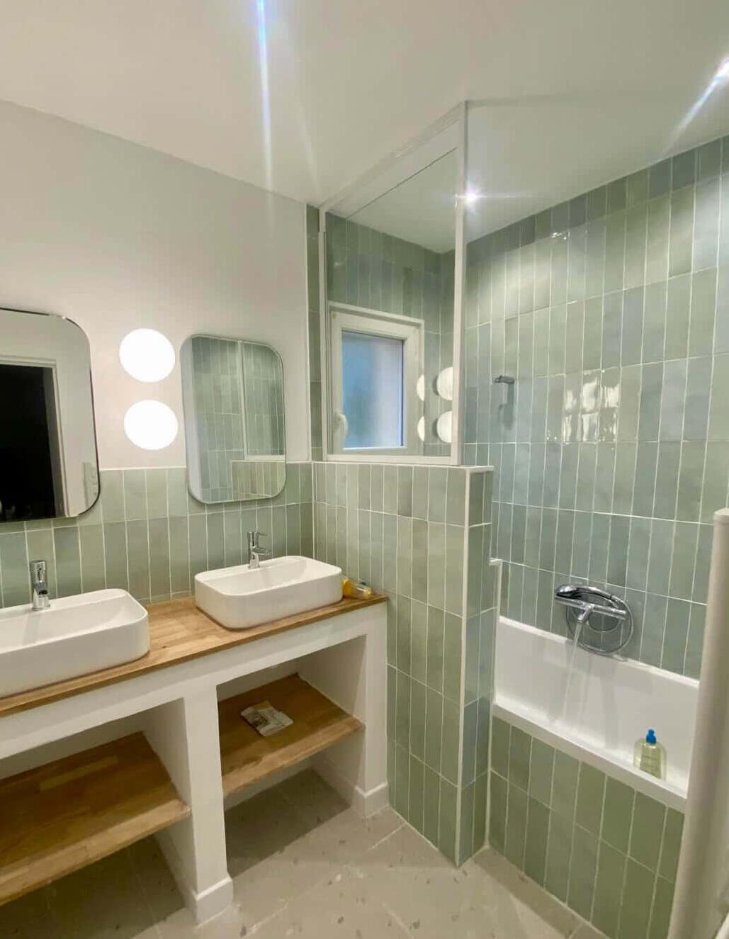 Salle de bain rénovée avec double vasque en bois, carrelage vert sauge en zellige et douche vitrée, réalisation Atelier Luzons